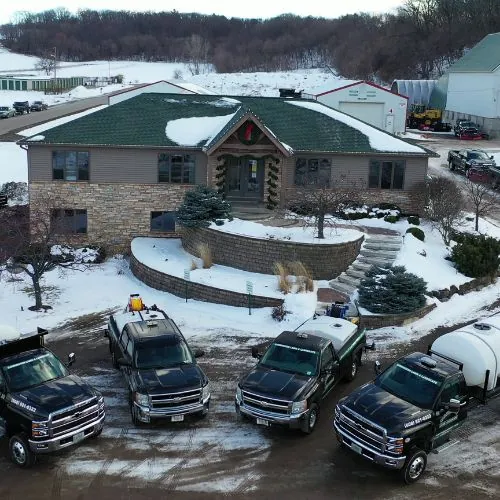 Fleet of snow and ice management trucks parked in front of a commercial building with a snow-covered landscape in Madison, WI