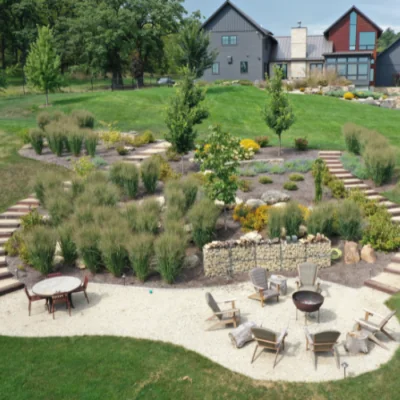 Aerial view of a modern landscaped backyard with a gravel patio, seating areas, and a fire pit by hardscape design contractors in Middleton, WI